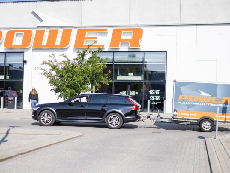 Bil med gratis Freetrailer foran POWER-butik – viser stærk synlighed og kundeservicefordel ved at blive partner.